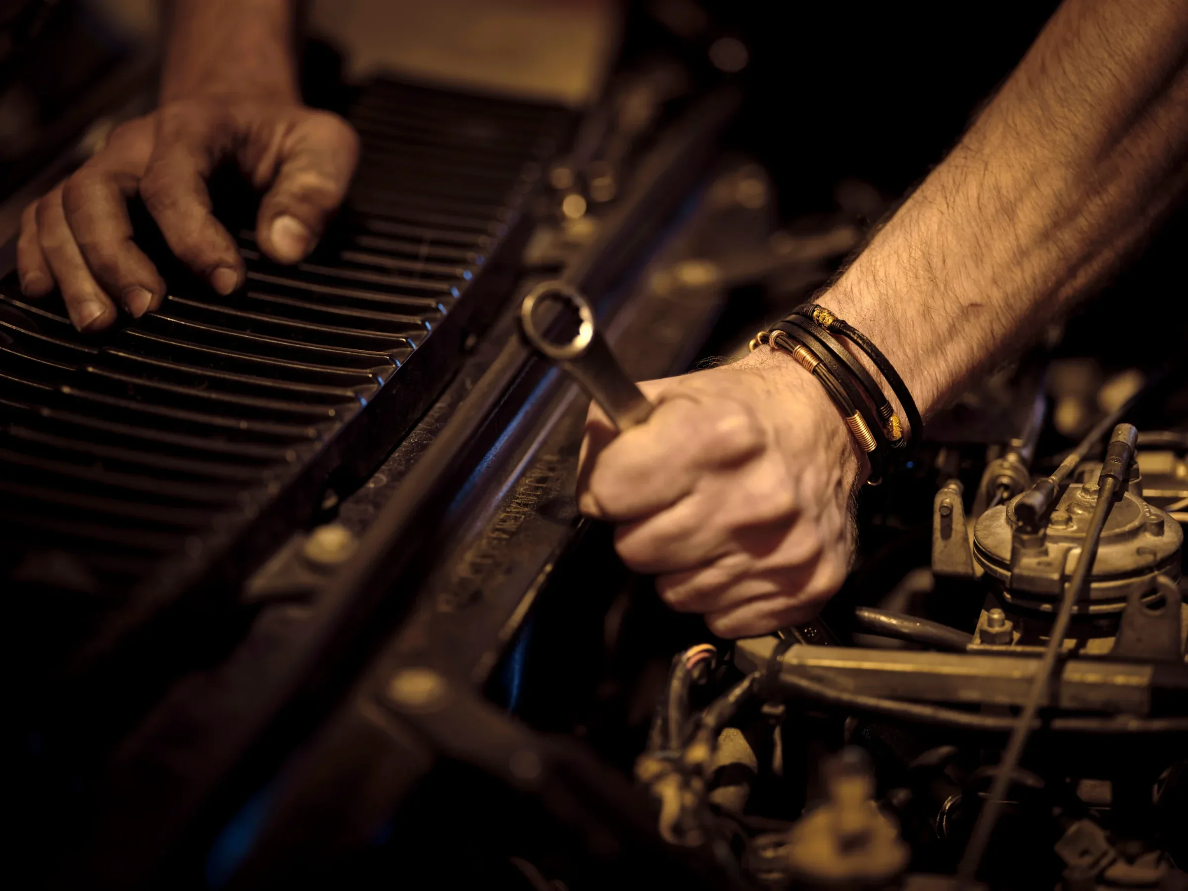 Hands working on an engine bay with a spanner